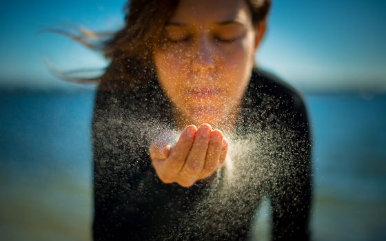 girl blowing sand